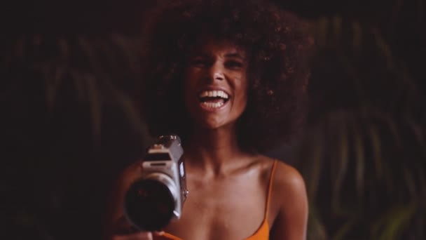 Γυναίκα με αφρό μαλλιά σε πορτοκαλί φόρεμα χρησιμοποιώντας Vintage 8mm κάμερα — Αρχείο Βίντεο
