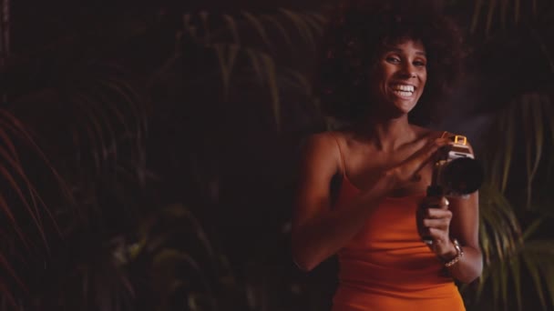 穿着橙色衣服的非洲裔妇女使用8mm的古旧相机 — 图库视频影像