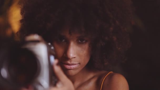 Mulher com cabelo afro no vestido laranja usando câmera vintage de 8mm — Vídeo de Stock