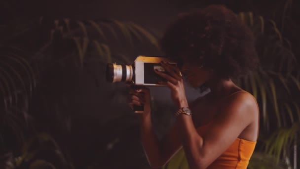 Mulher com cabelo afro filmando com câmera vintage de 8mm — Vídeo de Stock