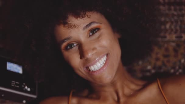 Женщина с африканскими волосами улыбается винтажной 8-мм камерой — стоковое видео