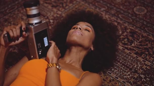 Mulher com cabelo afro no vestido laranja usando câmera vintage de 8mm — Vídeo de Stock