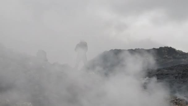Fotograf printre fumul gros pe stâncile câmpului de lavă — Videoclip de stoc