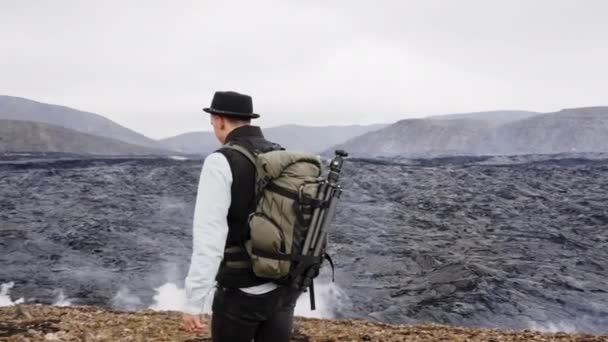 写真家が歩くと溶岩フィールドによって岩の上に座って — ストック動画