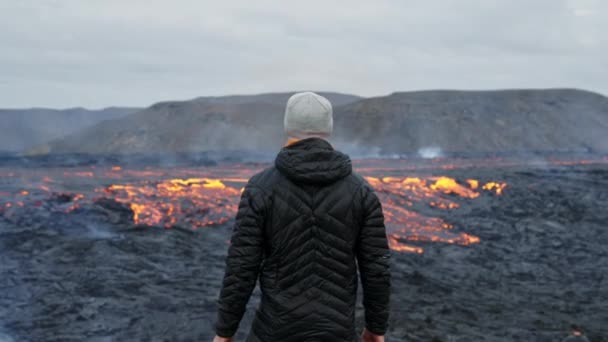 Hombre mirando hacia fuera sobre el flujo de lava en el paisaje en llamas — Vídeos de Stock