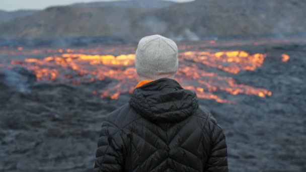 Hombre mirando hacia fuera sobre el flujo de lava en el paisaje en llamas — Vídeo de stock
