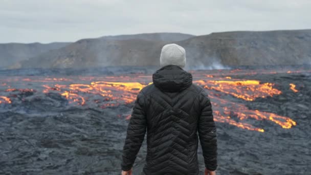 Hombre mirando hacia fuera sobre el flujo de lava en el paisaje en llamas — Vídeo de stock