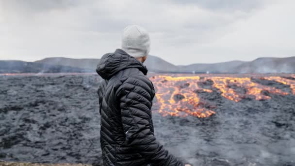 Fotograaf kijkend door camera naar vloeiende Lava in landschap — Stockvideo
