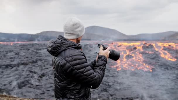 Fotógrafo mirando a través de la cámara para fluir lava en el paisaje — Vídeos de Stock