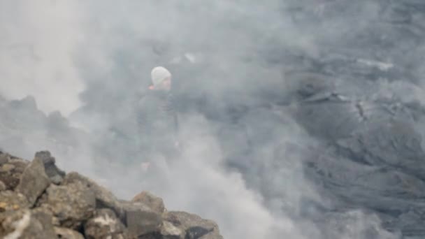 Fotograf hält Kamera inmitten rauchender Lavafelder — Stockvideo