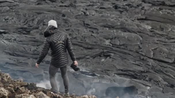 Fotógrafo caminando sobre rocas entre fumar campo de lava — Vídeos de Stock