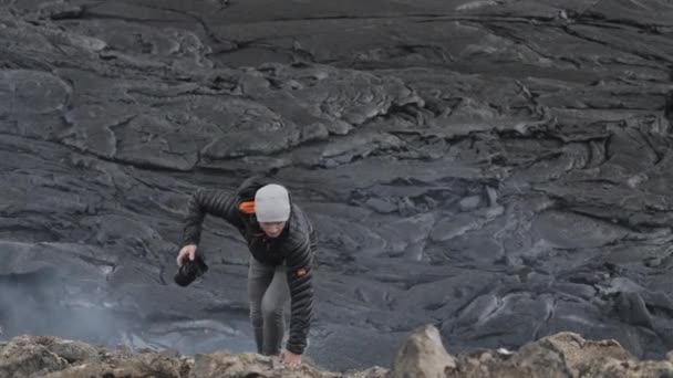 Fotografo che cammina sulle rocce tra il fumo campo di lava — Video Stock