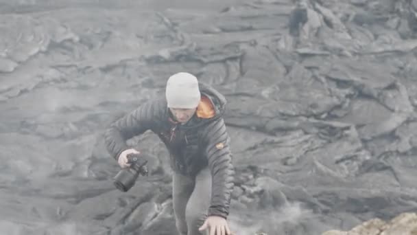 Fotógrafo caminando sobre rocas entre fumar campo de lava — Vídeo de stock