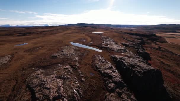 Drone vlucht over rotsachtige en schaarse landschap met meren reflecterende zon — Stockvideo