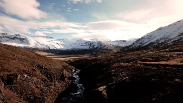 Беспилотник летит по течению к заснеженным горам — стоковое видео