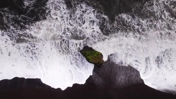 Vôo do drone para a pilha do mar em Surf de Surging na praia preta da areia — Vídeo de Stock