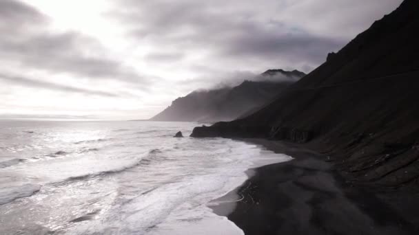 Drone Flight över vågor och svart strand mot Mist Täckt berg — Stockvideo