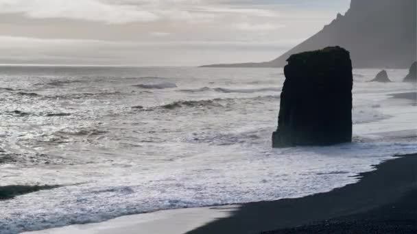 Zwart zand strand met zee stapel en witte branding — Stockvideo