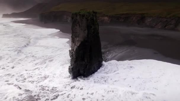 Κηφήνας πτήση τόξου γύρω από τη θάλασσα στοίβα σε λευκό surf στη μαύρη άμμο παραλία — Αρχείο Βίντεο