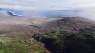 Sisli tepelerin ve nehrin üzerinden kıyı şeridine doğru insansız hava aracı uçuşu