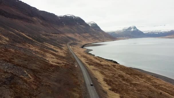 Voiture de suivi de drone conduisant par le fjord et vers les montagnes — Video