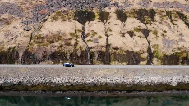 Dron strzał samochodu jazdy na drodze obok Mountainside i Fjord — Wideo stockowe