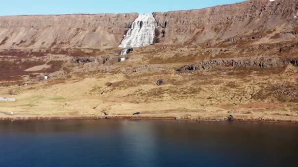 Drone de carro dirigindo ao lado do fiorde com cachoeira de montanha — Vídeo de Stock