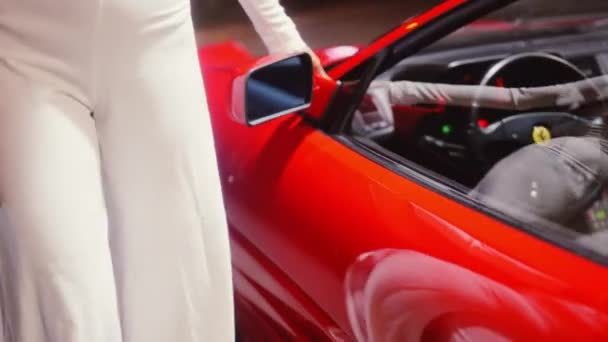 Женщина в комбинезоне, проходящая мимо и трогающая Красную Феррари на заправке — стоковое видео