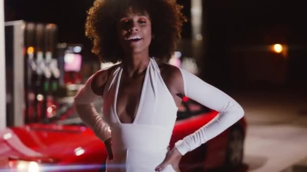 Vrouw met afro in jumpsuit poseren door Ferrari 348 in tankstation — Stockvideo