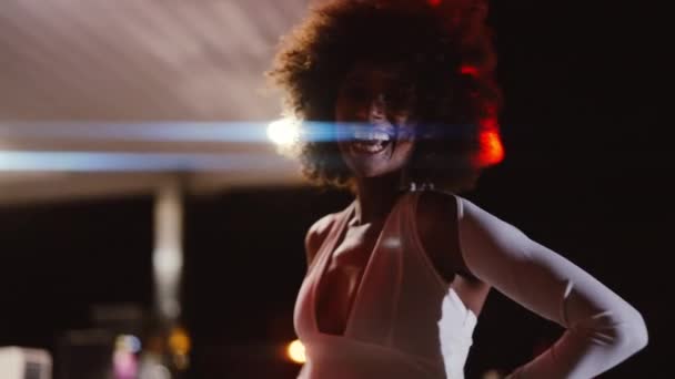 Donna con afro in tuta posa in distributore di benzina di notte — Video Stock