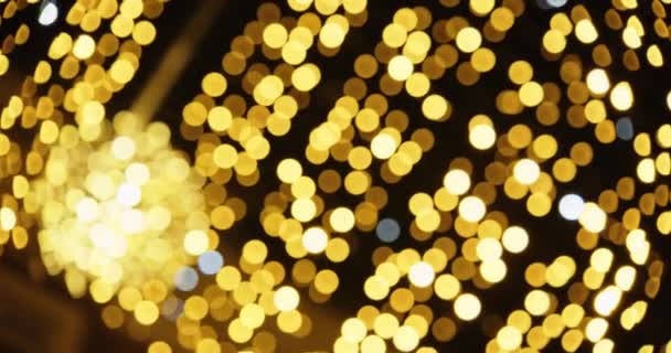 Disparo desenfocado de brillantes luces doradas de Navidad contra el cielo nocturno — Vídeos de Stock