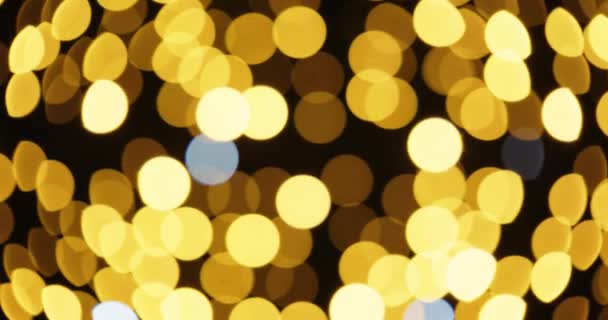 Tiro desfocado de luzes de Natal douradas cintilantes contra céu noturno — Vídeo de Stock