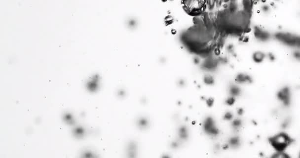 Folyadékot öntenek a vízbe, ami növekvő buborékokat okoz — Stock videók