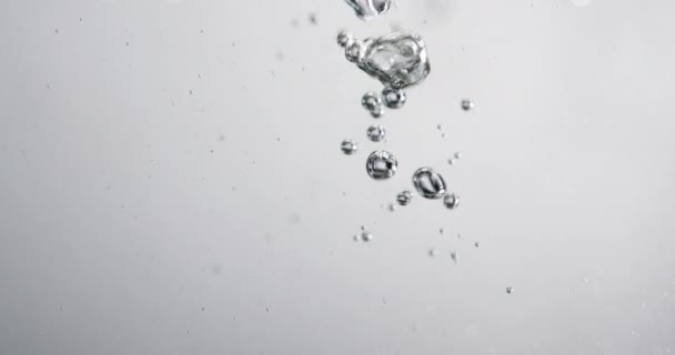 Bulles qui montent dans l'eau à mesure que le liquide y est versé — Video