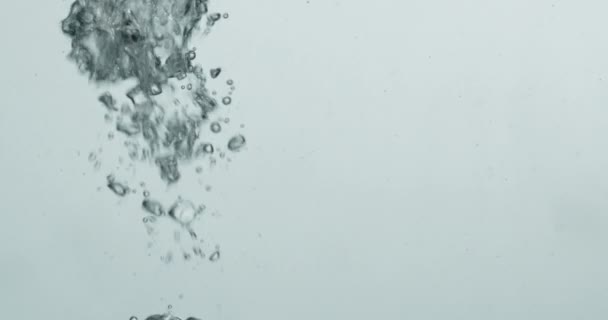 상승하는 거품을 일으키는 물 속으로 들어가는 액체 — 비디오