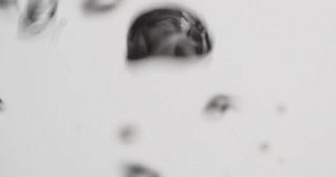 Beyaz arkaplana karşı kabarcıklarla akan su