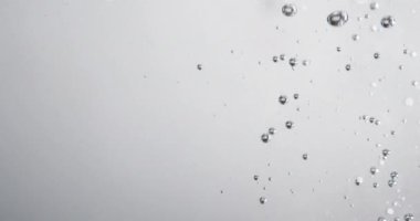 Beyaz arka plana karşı suda kabarcıklar hareket ediyor ve yükseliyor