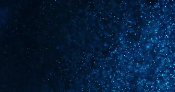 Μπλε φυσαλίδες και σωματίδια στο νερό σε μαύρο φόντο — Αρχείο Βίντεο