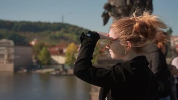 Femme protégeant les yeux du soleil comme elle voit la rivière du pont Charles — Video