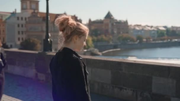 Ung kvinna vandrar längs Sunny Charles Bridge för att se floden — Stockvideo