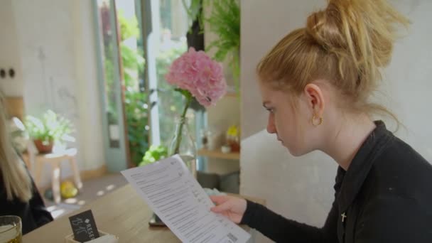 Jonge vrouw kiezen uit menu in Cafe In Praag — Stockvideo