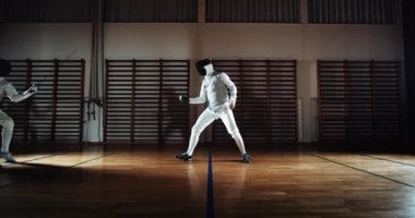 Eskrimciler birbirlerini kılıçlarıyla itiyor ve savuşturuyorlar.