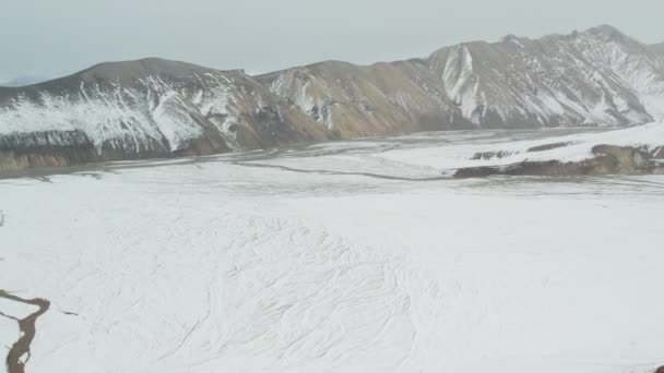 Drone sobre las montañas cubiertas de nieve con trenzado río abajo — Vídeos de Stock