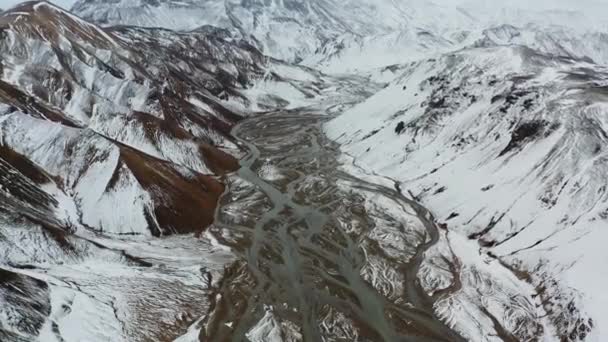 Drone sobre montañas cubiertas de nieve paisaje con lecho de río trenzado — Vídeos de Stock