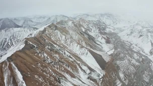Drone sobre picos de montanha nevados com leito de rio trançado abaixo — Vídeo de Stock