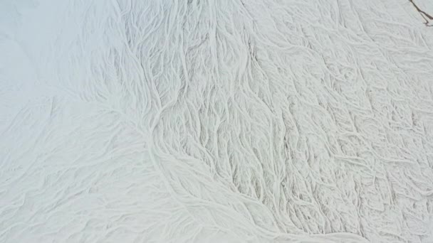 Беспилотник над покрытым снегом ландшафтом с замерзшим плетеным руслом реки — стоковое видео