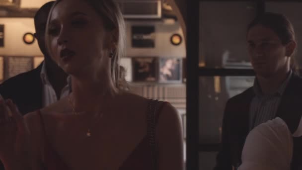 Жінка в барі з сигаретою і чоловіки пропонують запалити її для неї — стокове відео