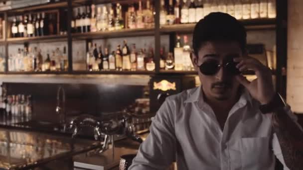 Hombre quitándose gafas de sol para leer en pasar mujer caminando en el bar — Vídeo de stock