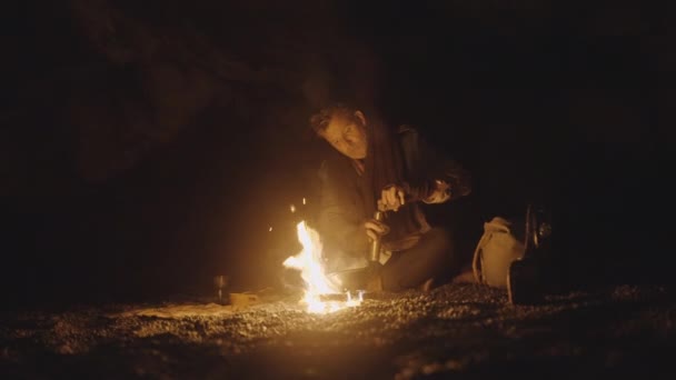 Adam gecenin bir yarısı kamp ateşinde eski kahve öğütücüsünü hazırlıyor. — Stok video