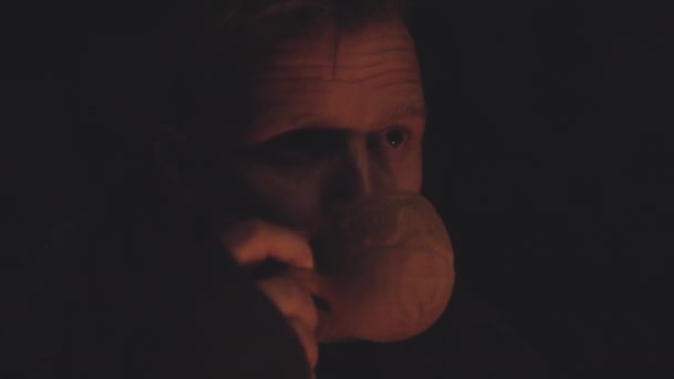 Чоловік у темній печері з обличчям, освітленим напоєм "Кемпфайр" — стокове відео